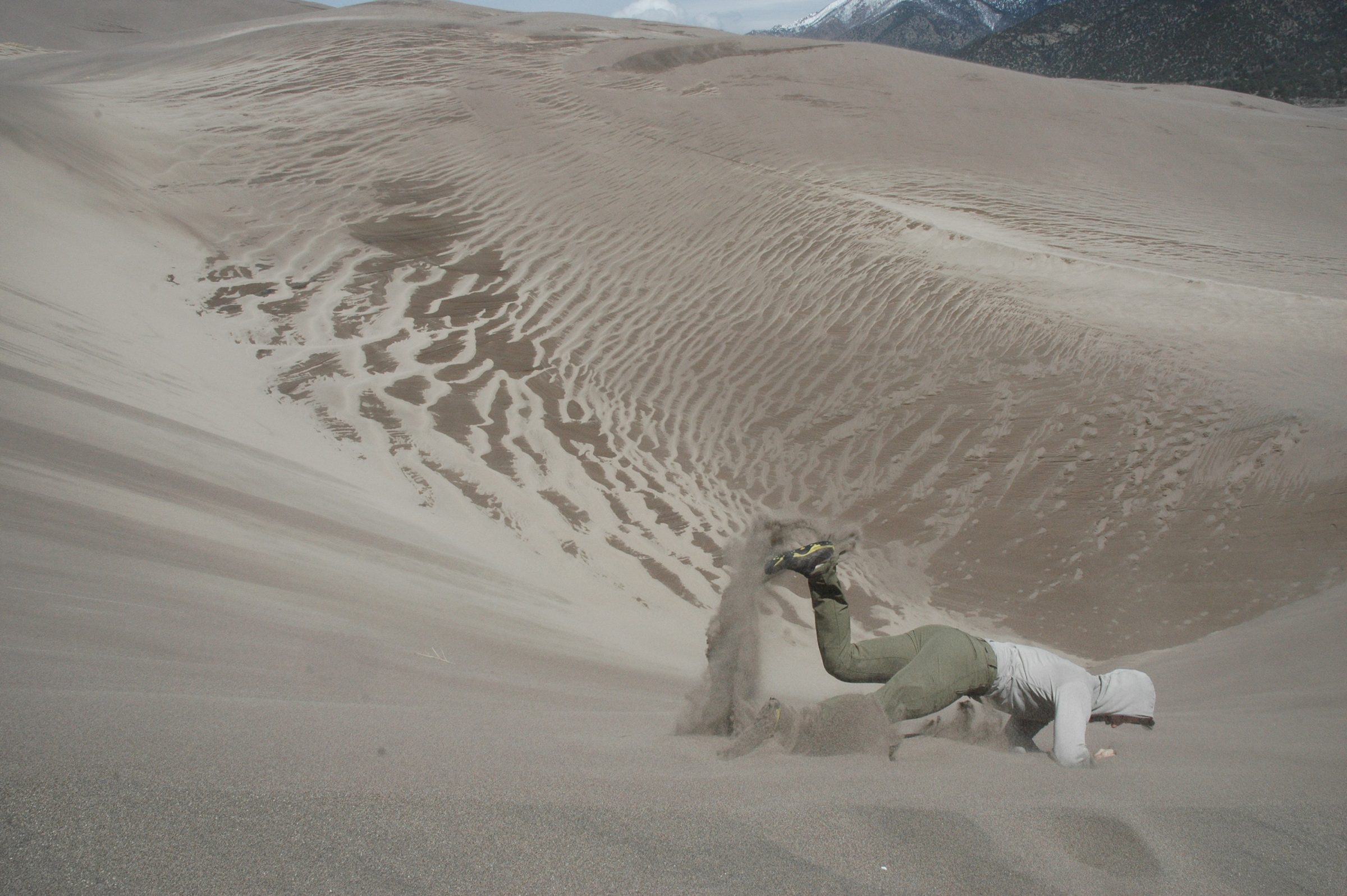 Jay tumbling headfirst down a steep sand dune