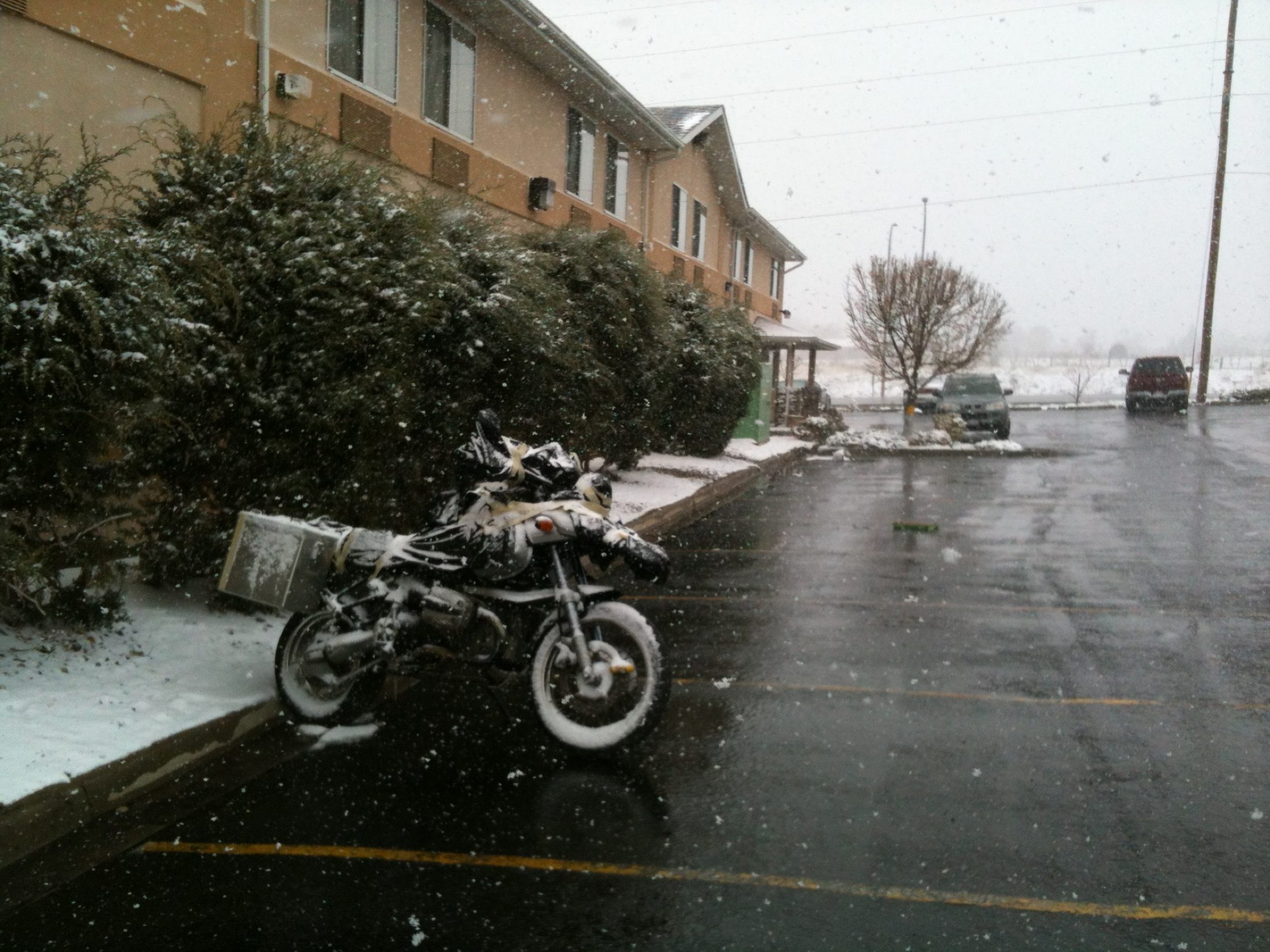Loaded motorcycle covered in snow outside a motel