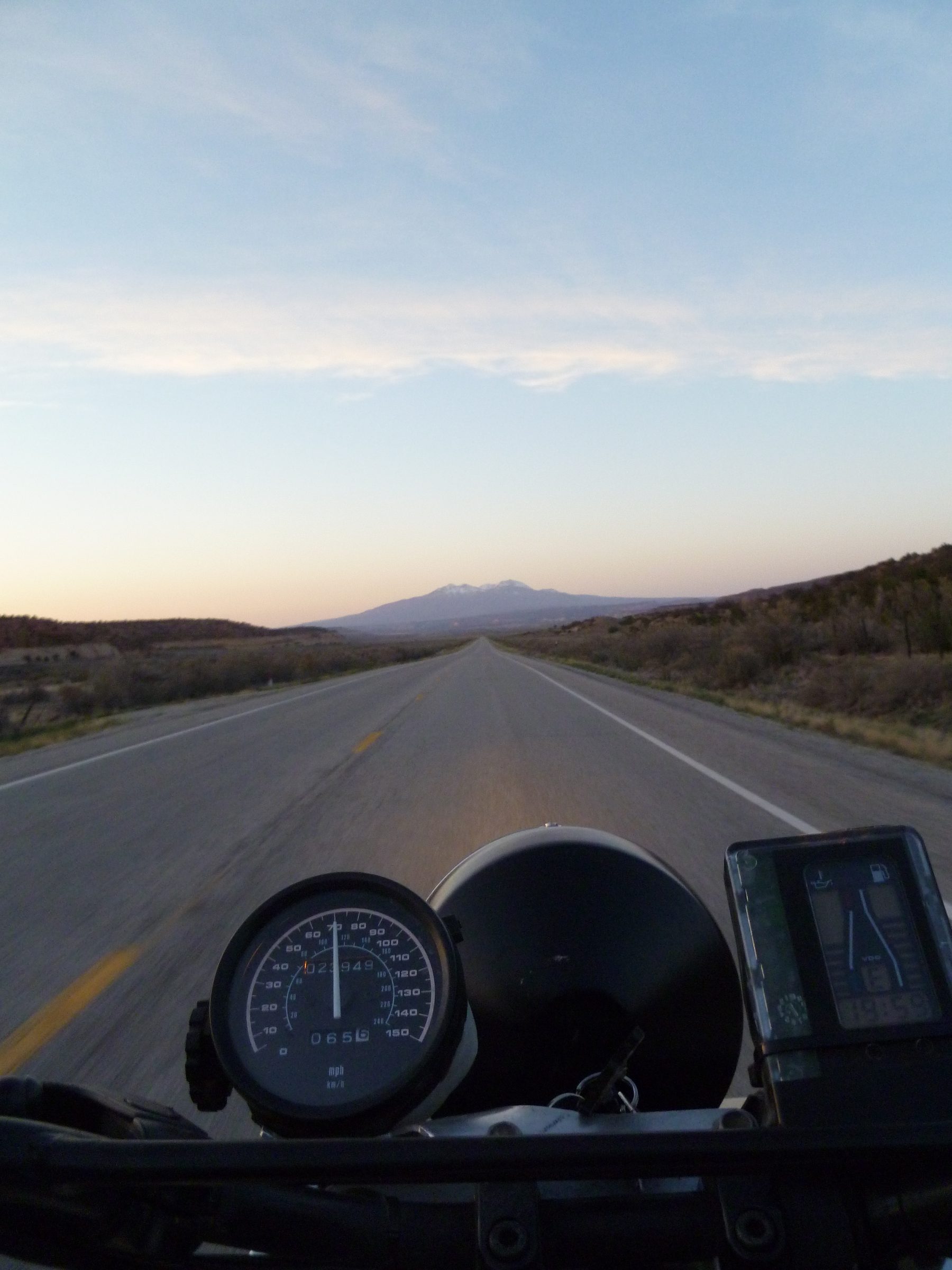 The road ahead viewed from a motorcycle, with mountains on the horizon